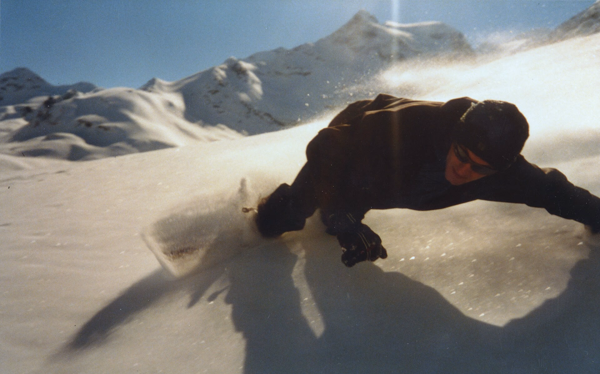 A snowboarder turning in deep powder